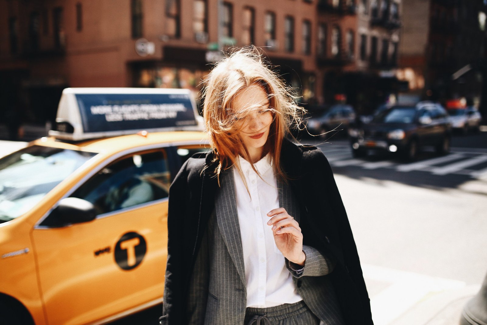 Blonde lady in black coat stands on the sunny street somewhere in New York city